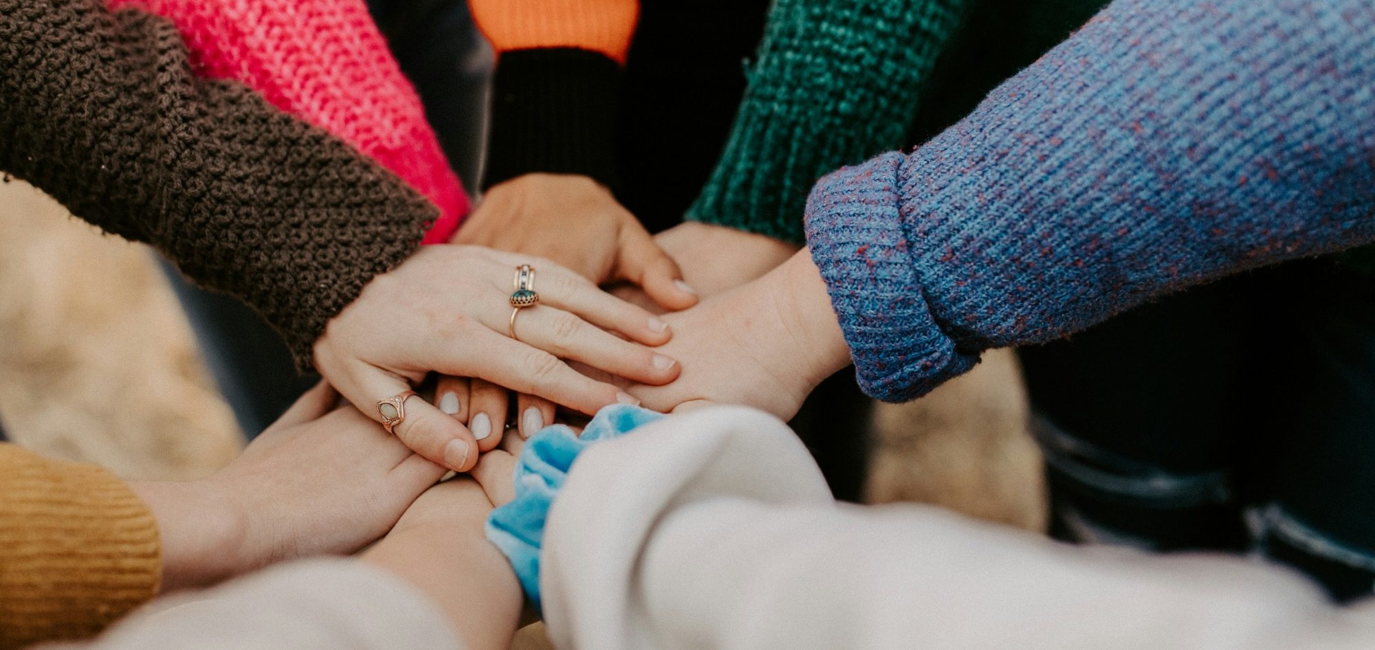 Photo by Hannah Busing on Unsplash A diverse group of hands stacking on top of each other in unity.